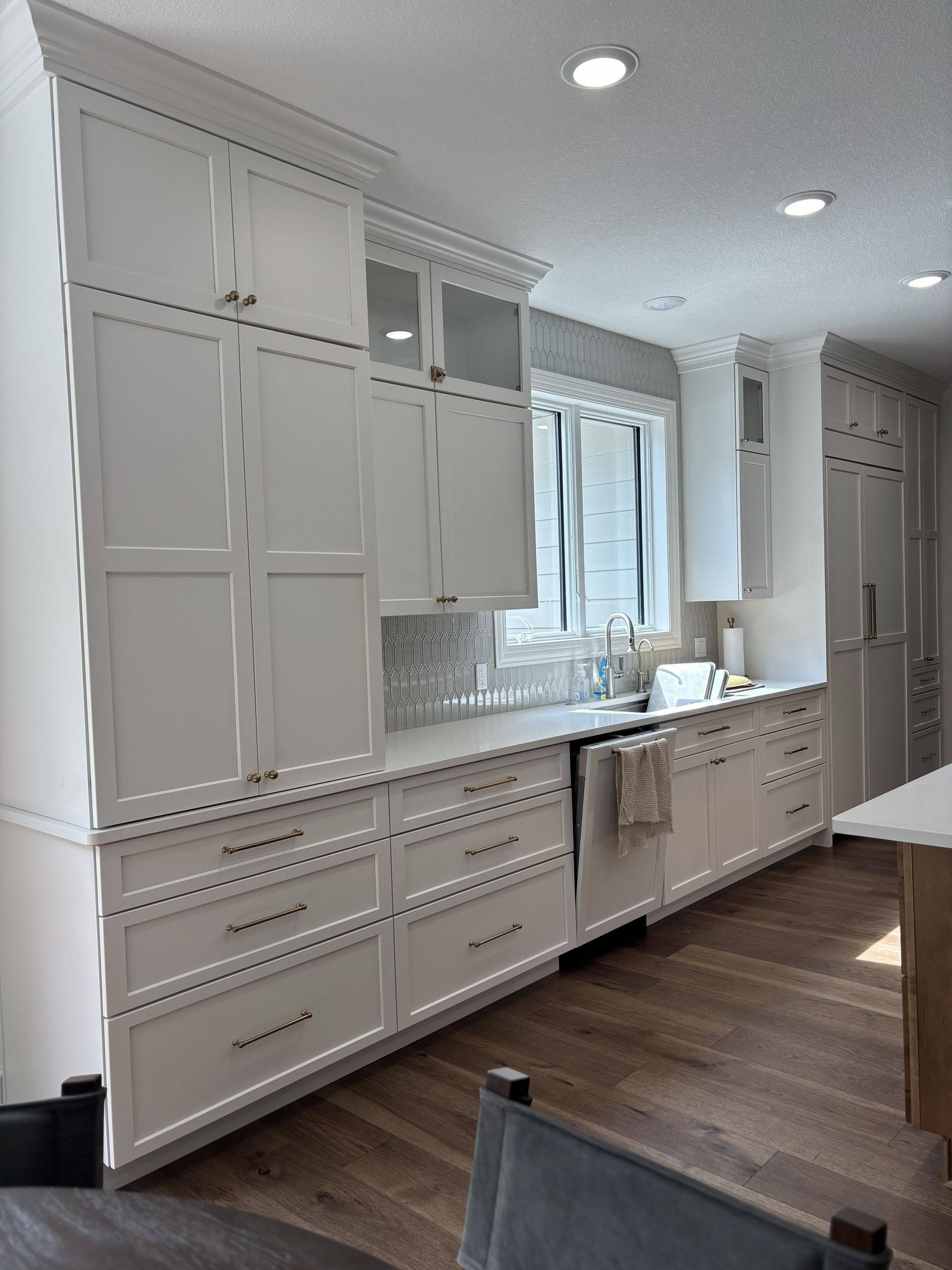White kitchen cabinets with light countertops and wooden floor.