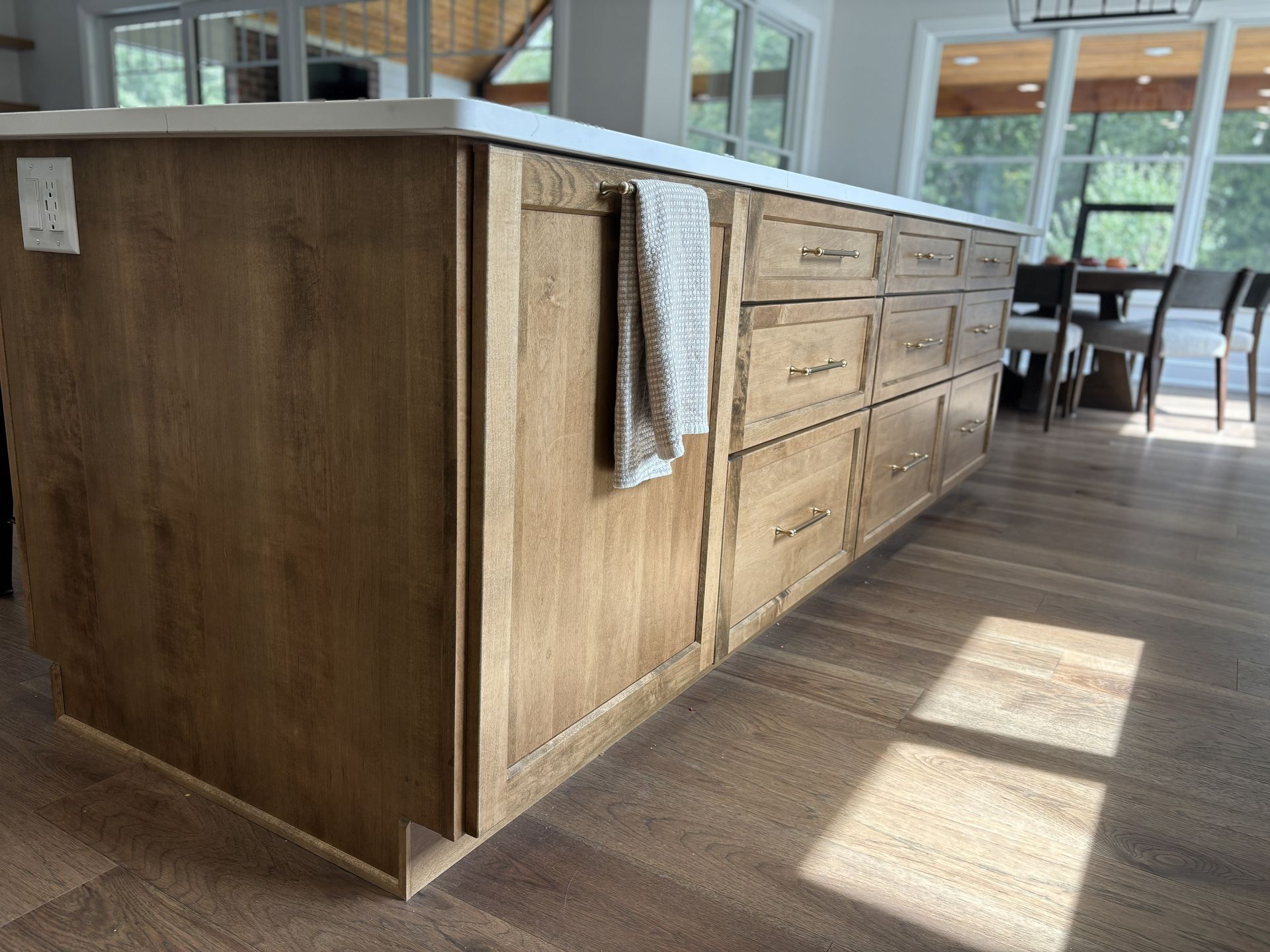 Wooden kitchen island with white countertop and drawers; a towel hangs on the side.
