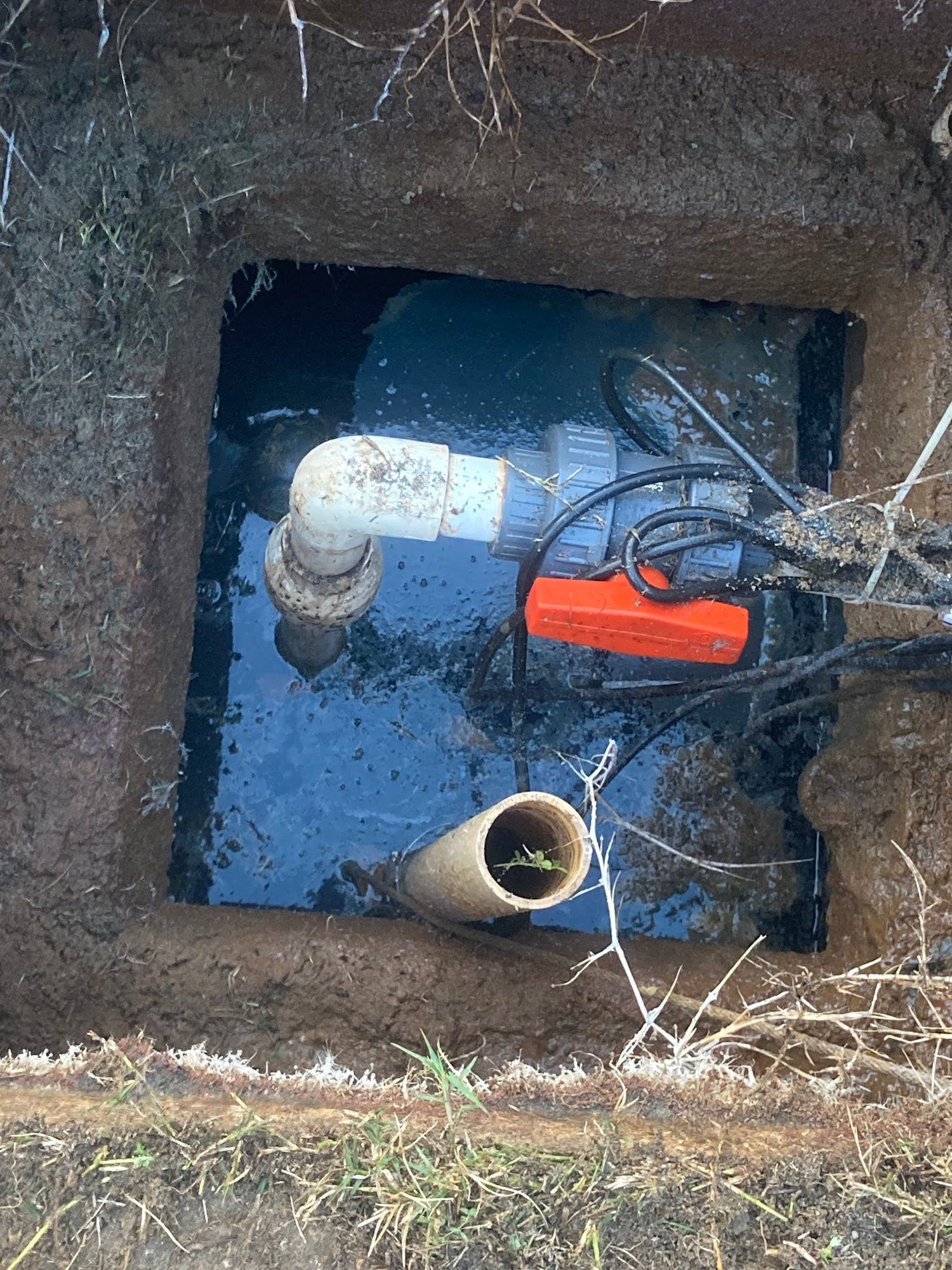 A hole in the ground filled with water and pipes.