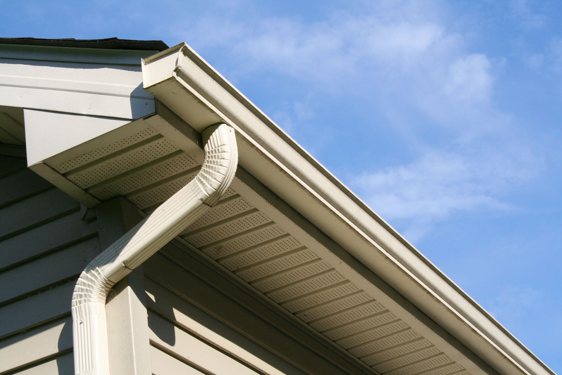 A man is installing a gutter on the roof of a house.