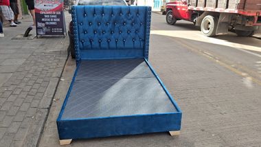 Sofá cama tapizado en azul expuesto al aire libre en una acera.