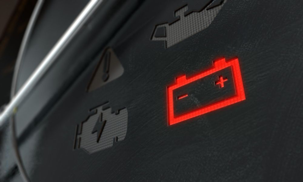 Een autodashboard met een rood batterijlampje erop
