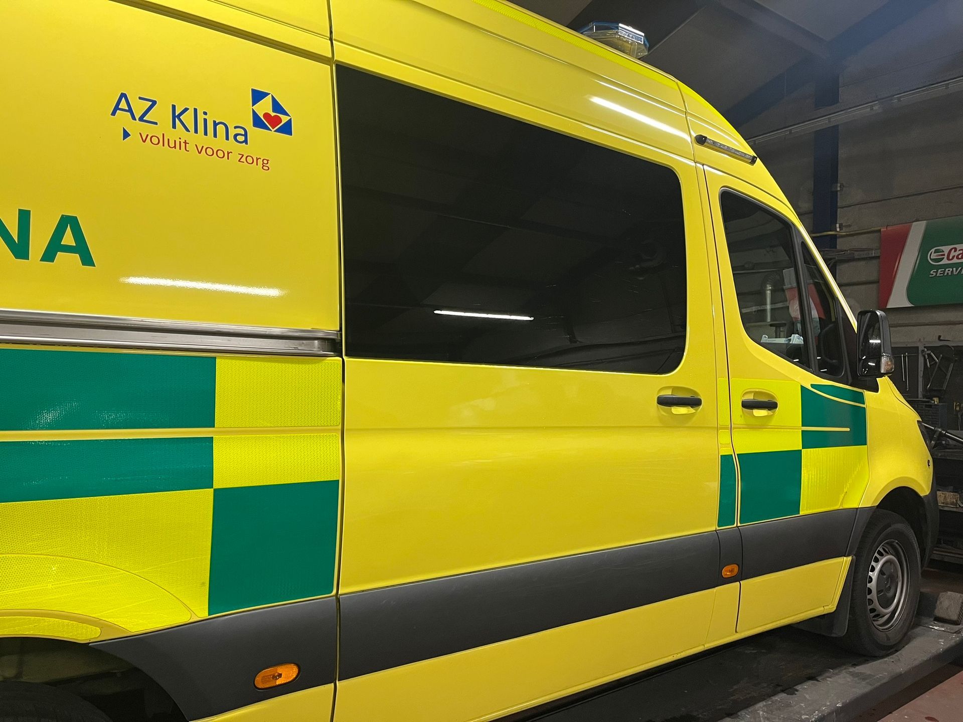 Een gele bestelwagen met op de zijkant het opschrift az klina