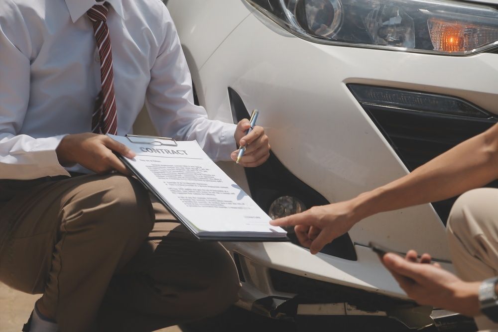 Een man ondertekent een document naast een witte auto.