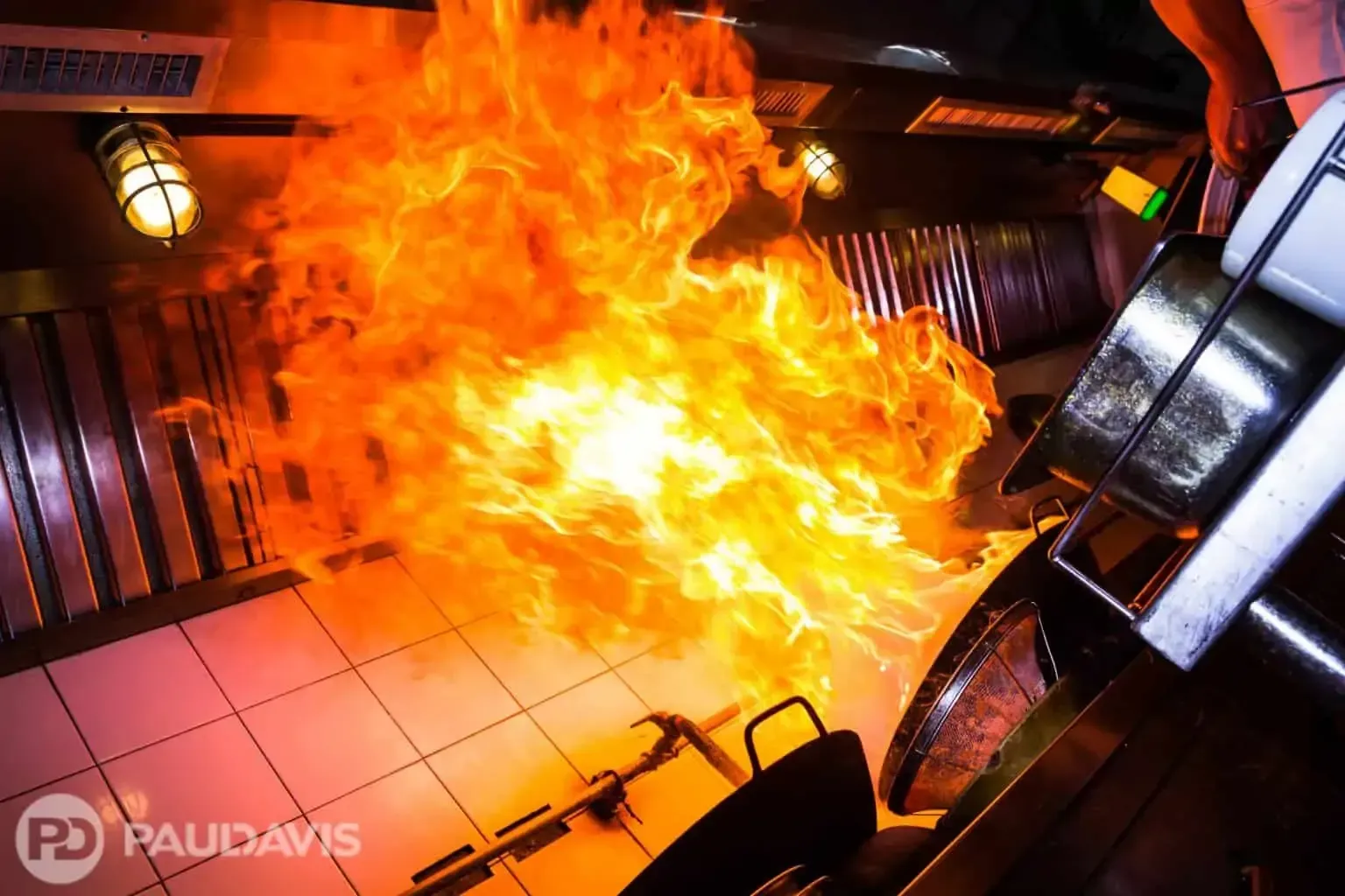 Fire erupting from a kitchen, flames engulfing equipment and surroundings.