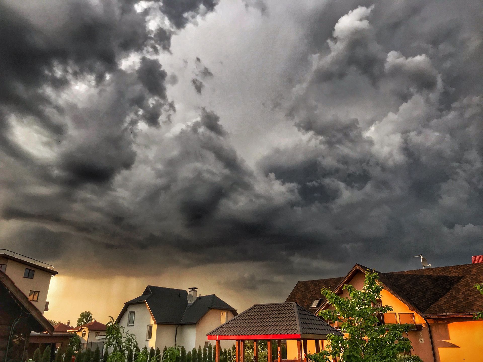 Dark grey storm clouds gathering over suburban homes before a summer storm