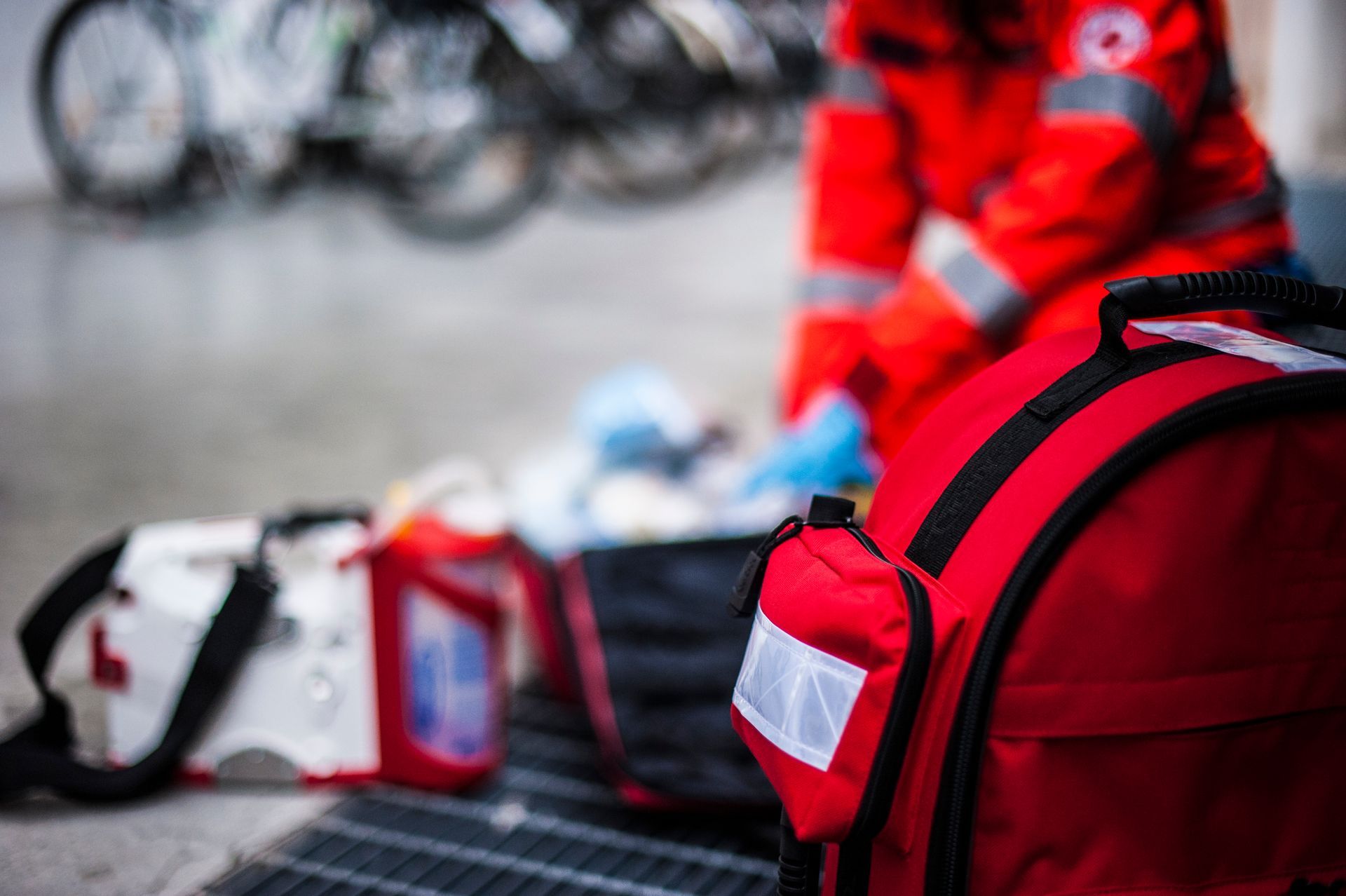 Red emergency responder gear and bags on the ground, with a person in a red uniform nearby
