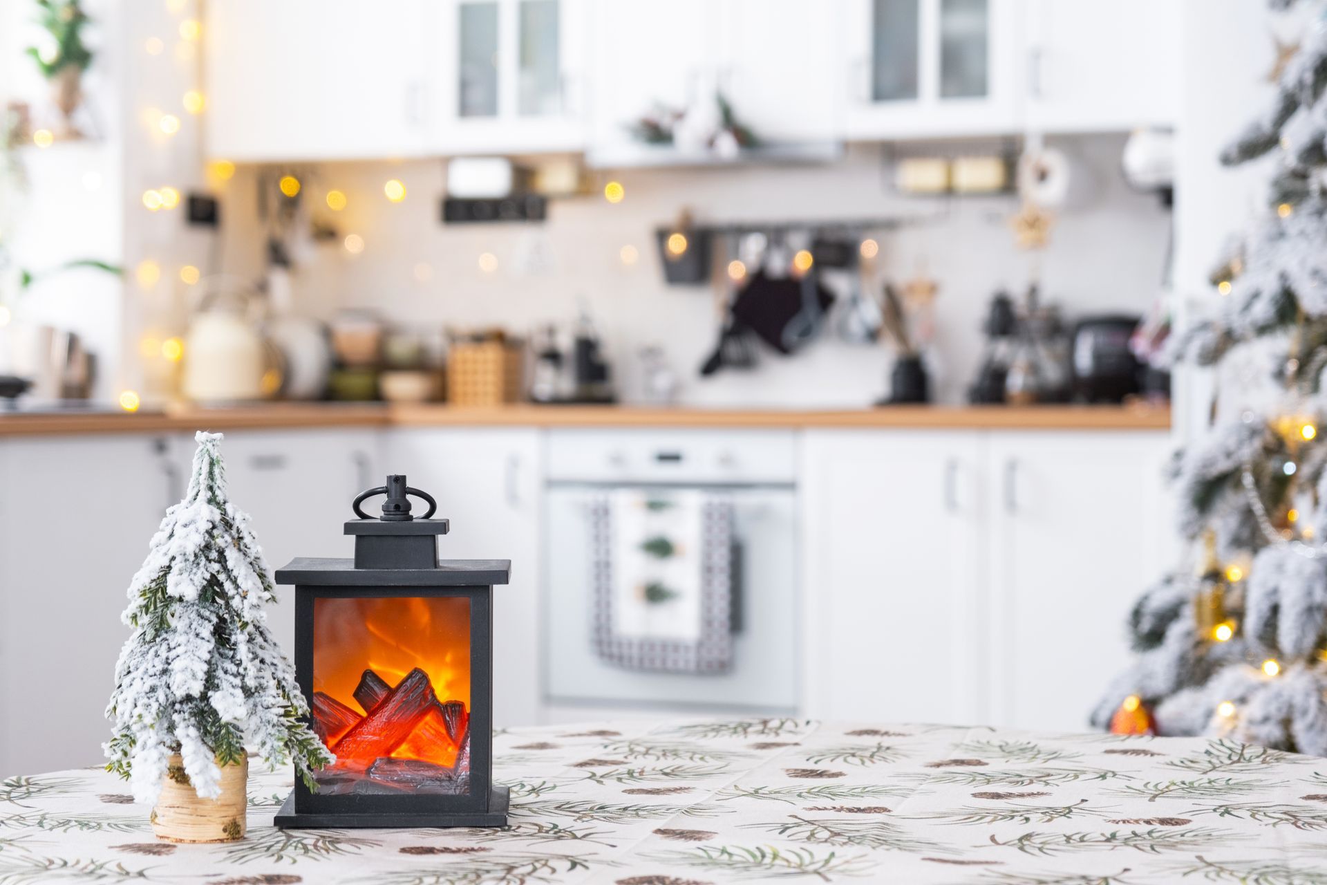 Cozy winter kitchen with a glowing lantern, frosted trees, and warm holiday lights on a patterned tablecloth