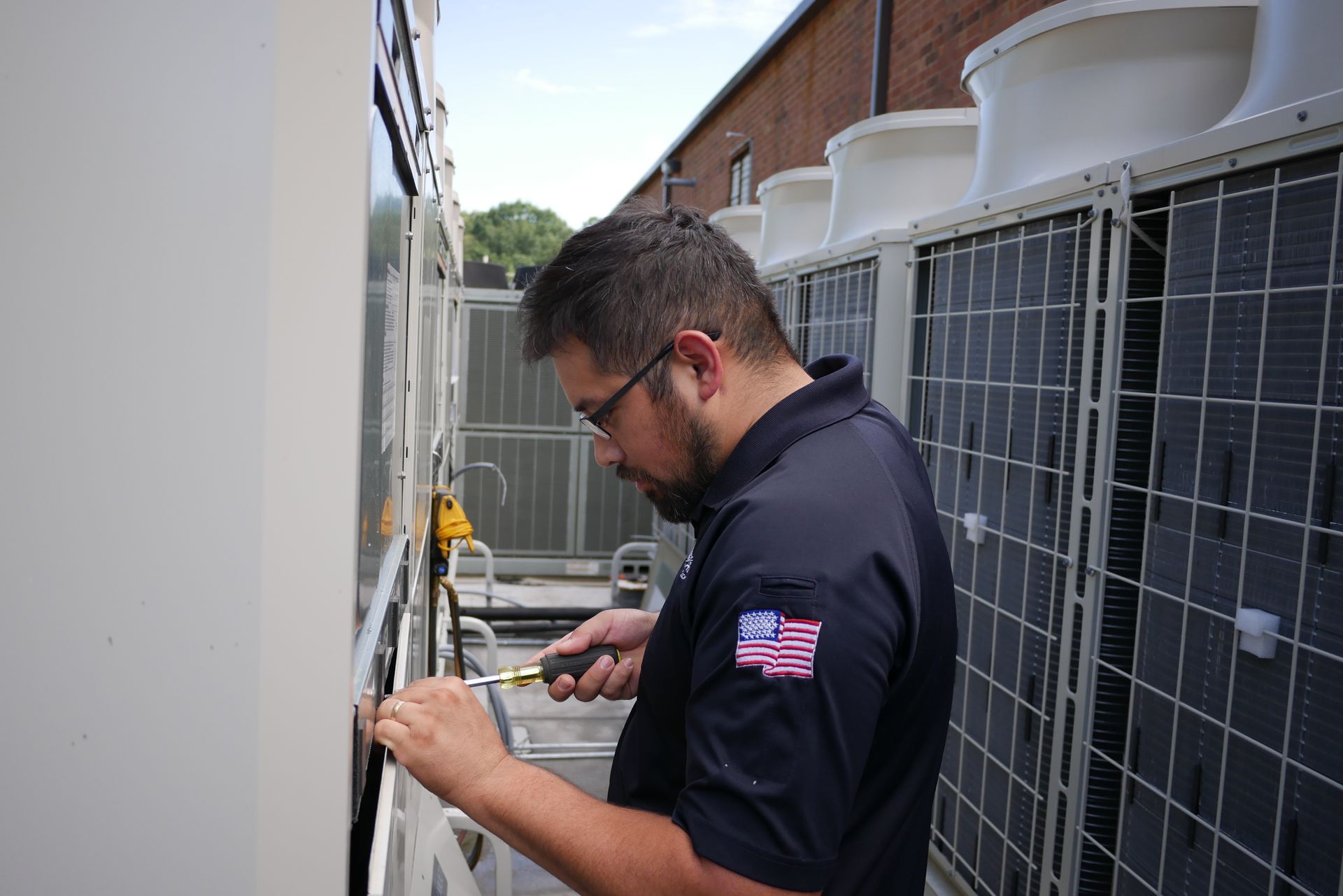 A man is working on an air conditioner outside of a building.
