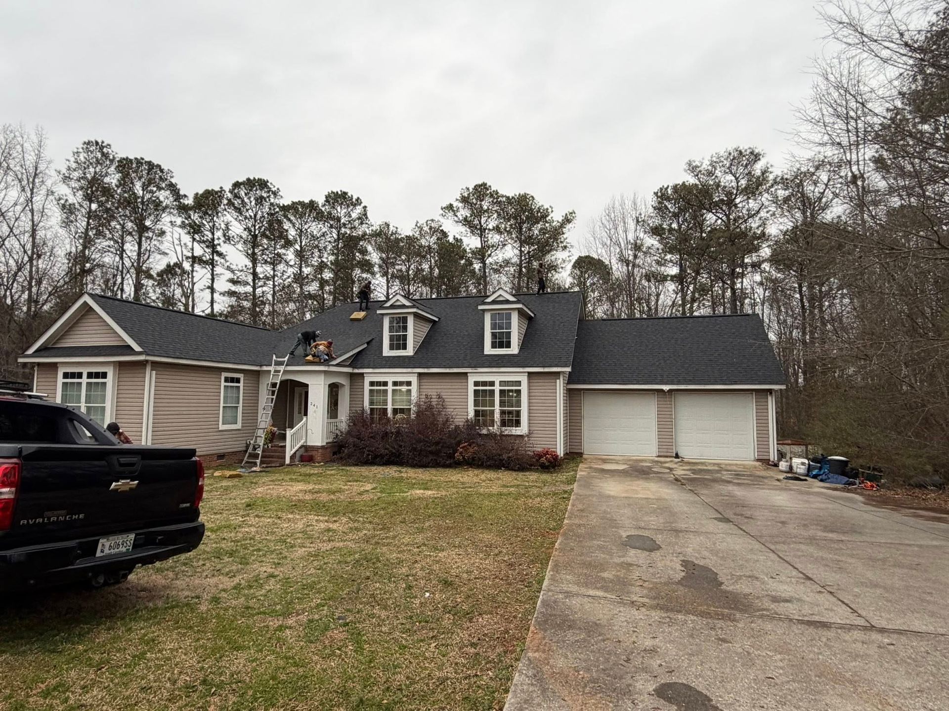 Suburban house with driveway, garage, and black pickup truck parked in the front yard