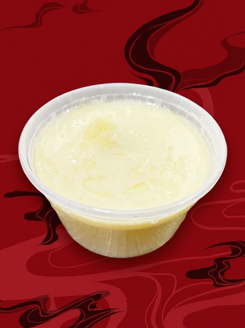 Small clear plastic cup filled with pale yellow dessert on a red patterned cloth