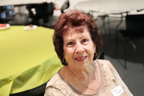 Smiling woman seated at a table with a lime-green tablecloth in a banquet hall