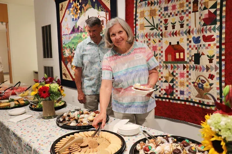 Woman serving dessert at a buffet table in a quilt-decorated room