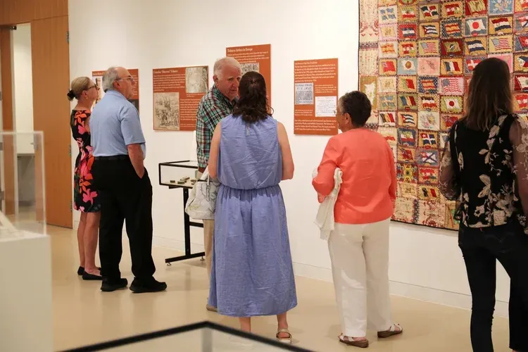 People viewing wall art in a gallery, with colorful artwork and display panels on the wall