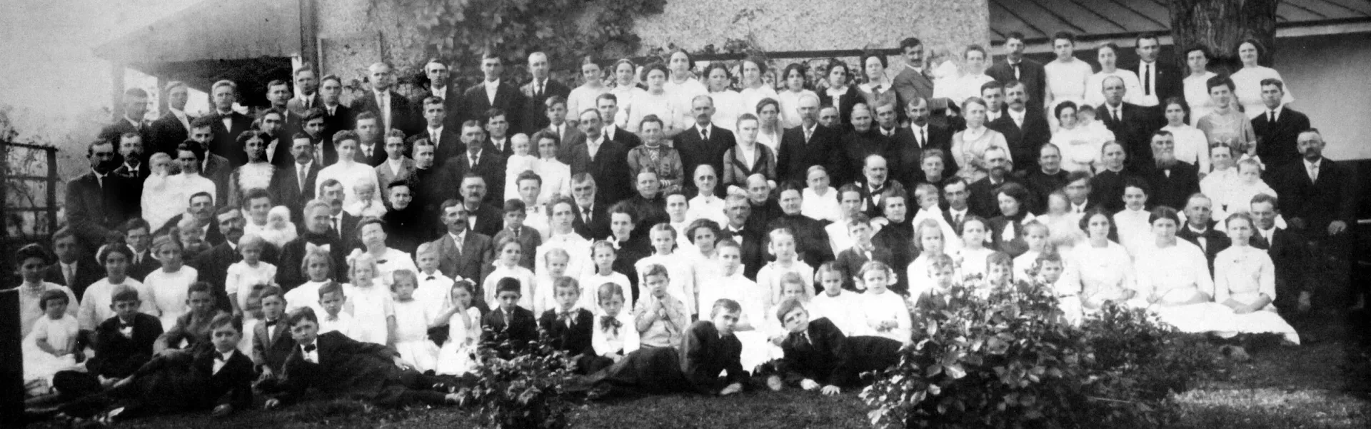 Large group posing outdoors in front of a building, in a black-and-white photo.
