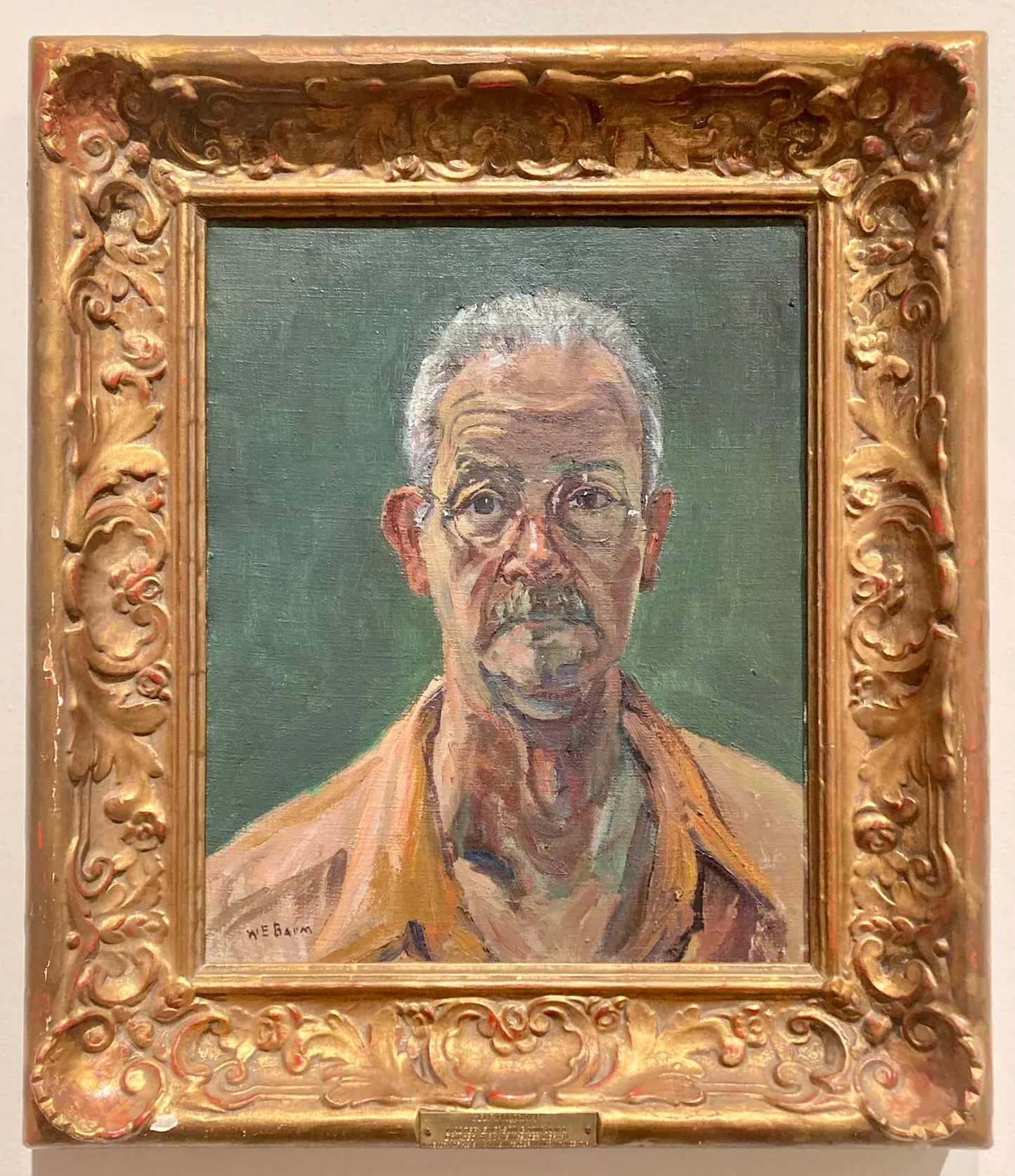 Framed oil portrait of a seated person with short gray hair against a green background