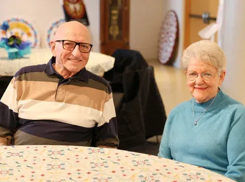 Two smiling people seated at a table in a cozy dining room