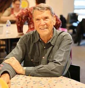 Smiling man seated at a table in a casual indoor setting