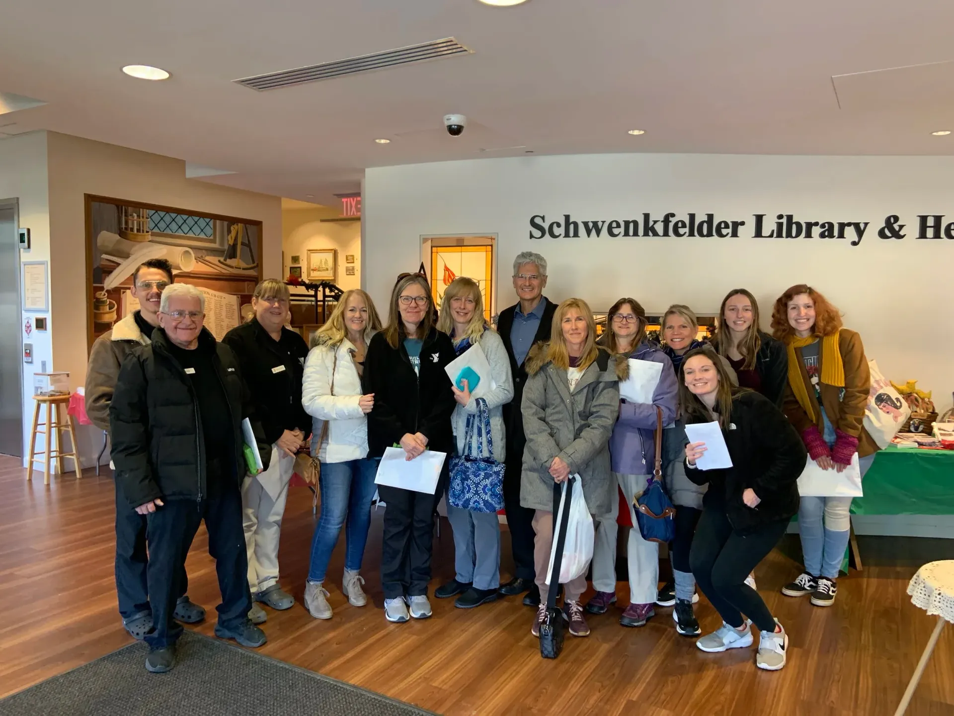 Group of people posing indoors at Schwenkfelder Library & Heritage Center, holding papers and smiling.