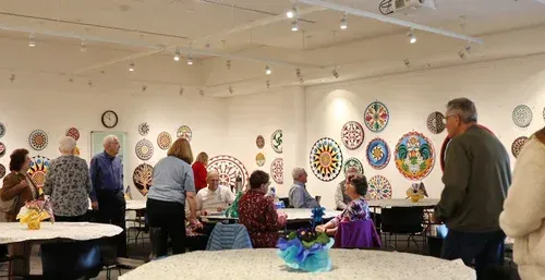 People gathered in a bright gallery with colorful circular artworks on the walls.