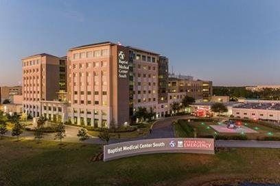 Hospital building at dusk with illuminated windows and a sign reading “Baptist Medical Center South”
