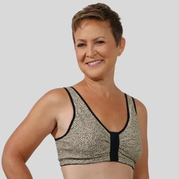 Smiling person in a beige patterned sports bra against a gray background
