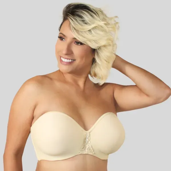 Smiling person in a beige strapless bra, hand behind head, against a plain background