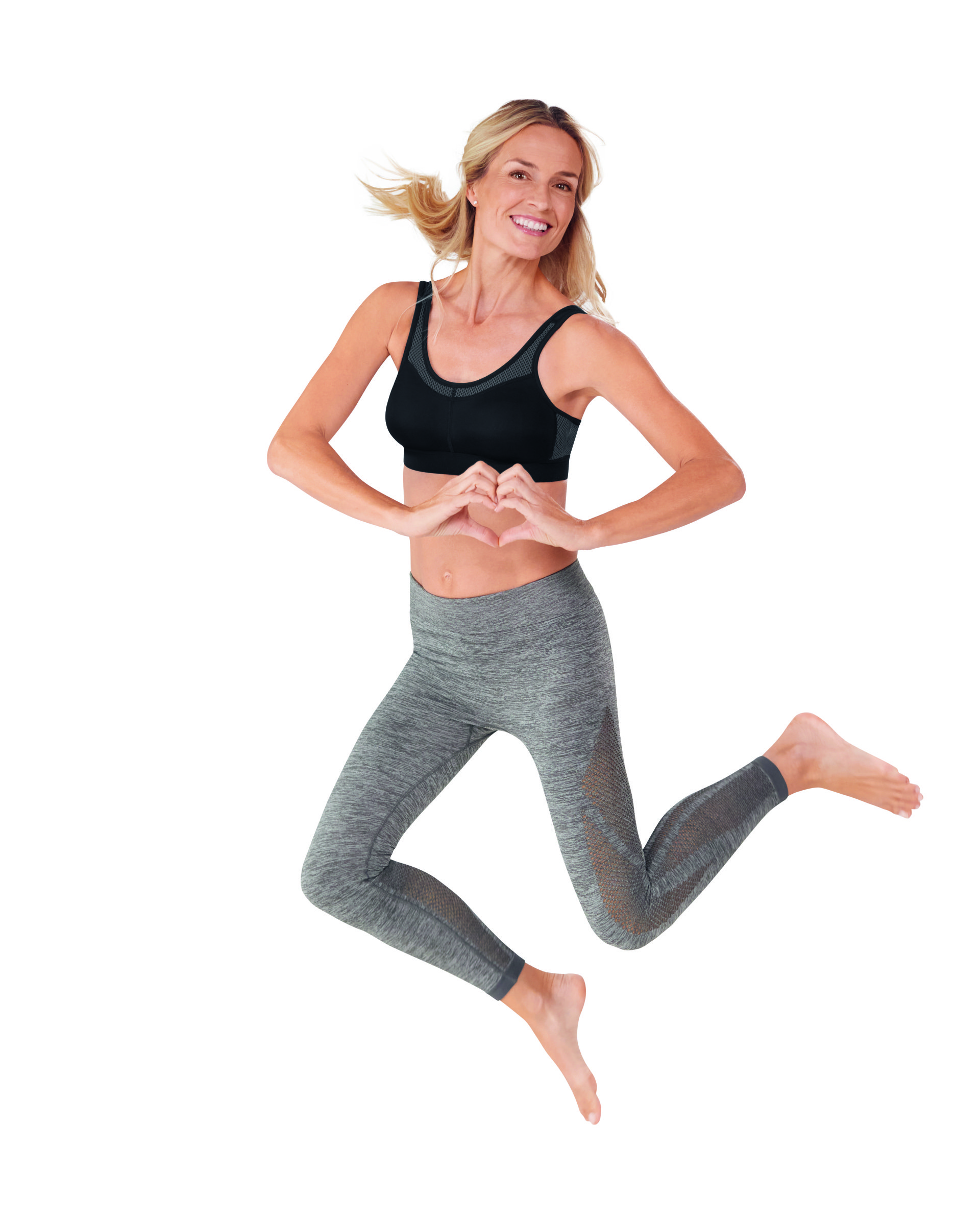 Woman in athletic wear jumping with a playful pose on a white background
