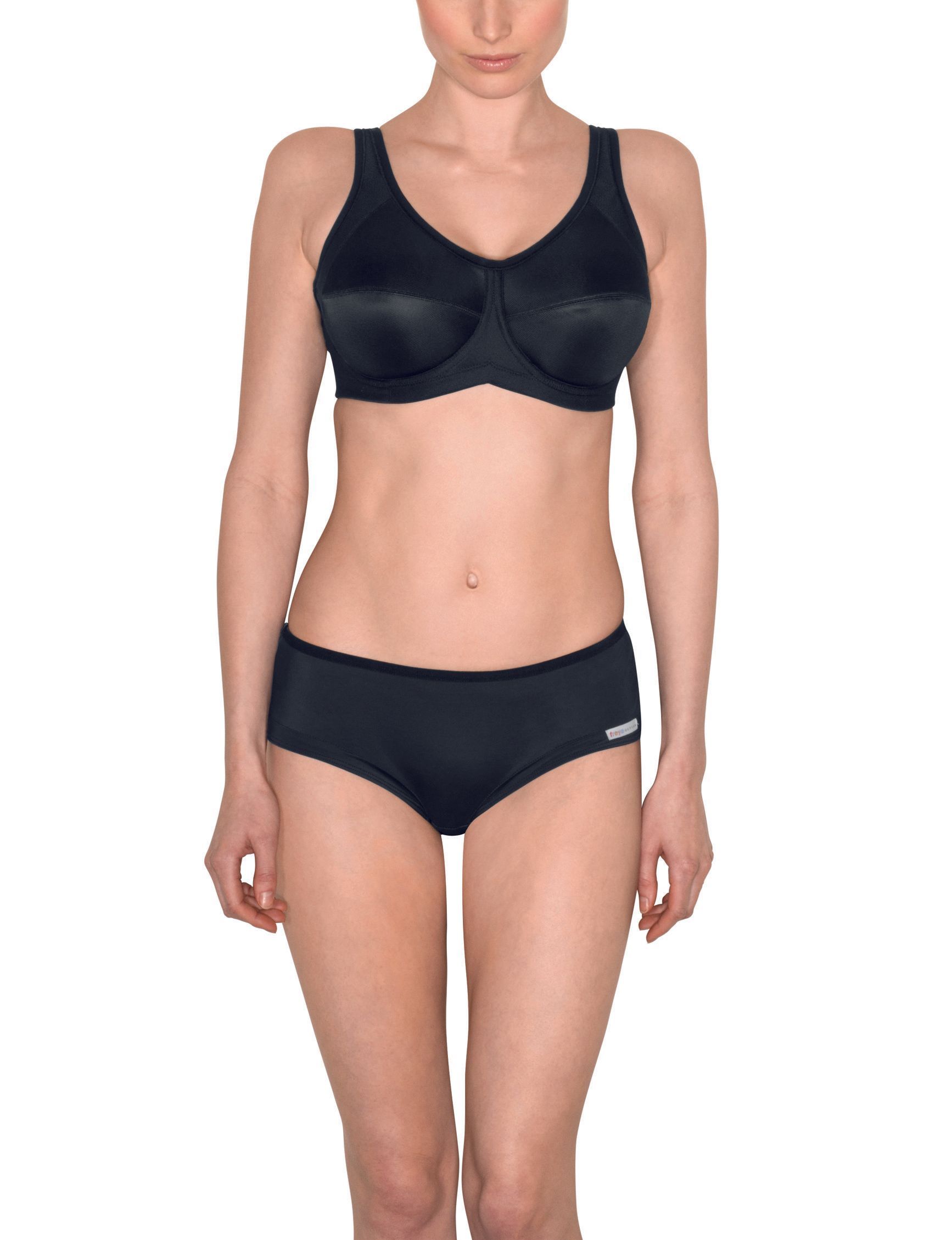 Person in black sports bra and briefs standing against a white background.