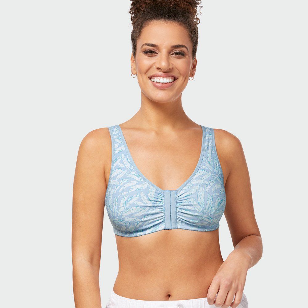 Smiling model wearing a light blue patterned sports bra on a white background