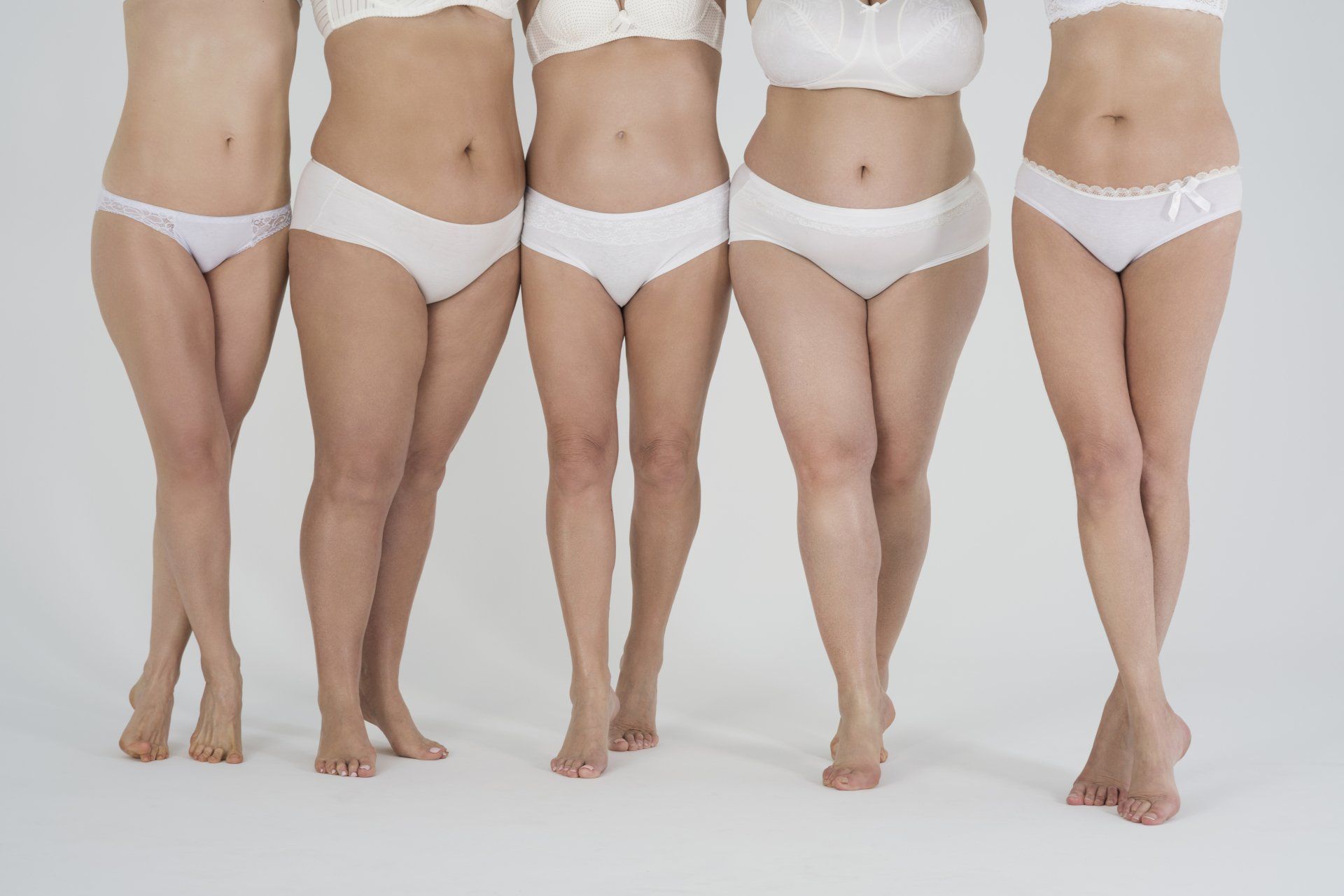 Four people in white underwear stand side by side against a plain white background.