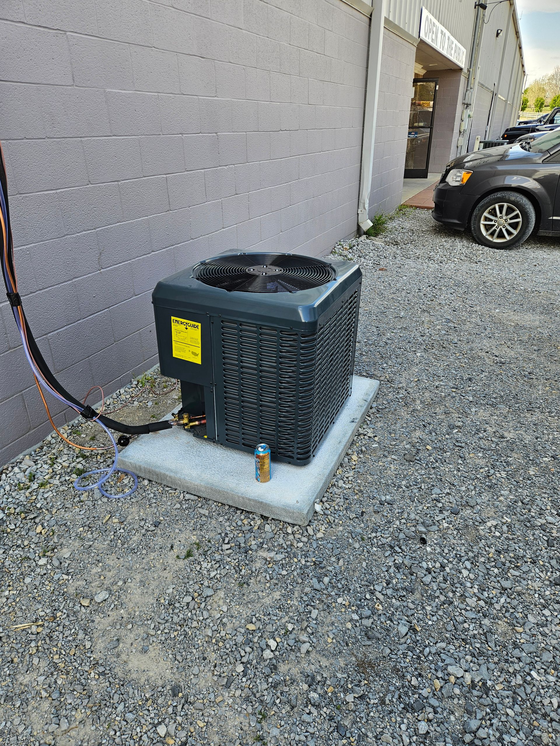 Air conditioning unit on a concrete pad next to a building, surrounded by gravel.