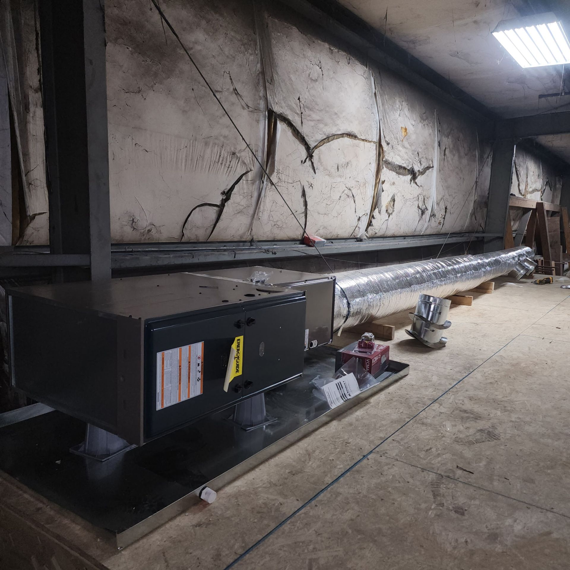 HVAC system installed in a room with damaged walls and ductwork.