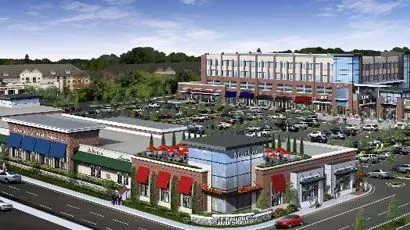 Aerial view of a shopping center with parking lot, storefronts, and surrounding buildings.