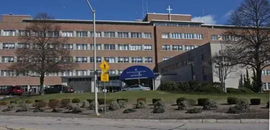 Brick office building behind a roadside sign and landscaped median under a blue sky