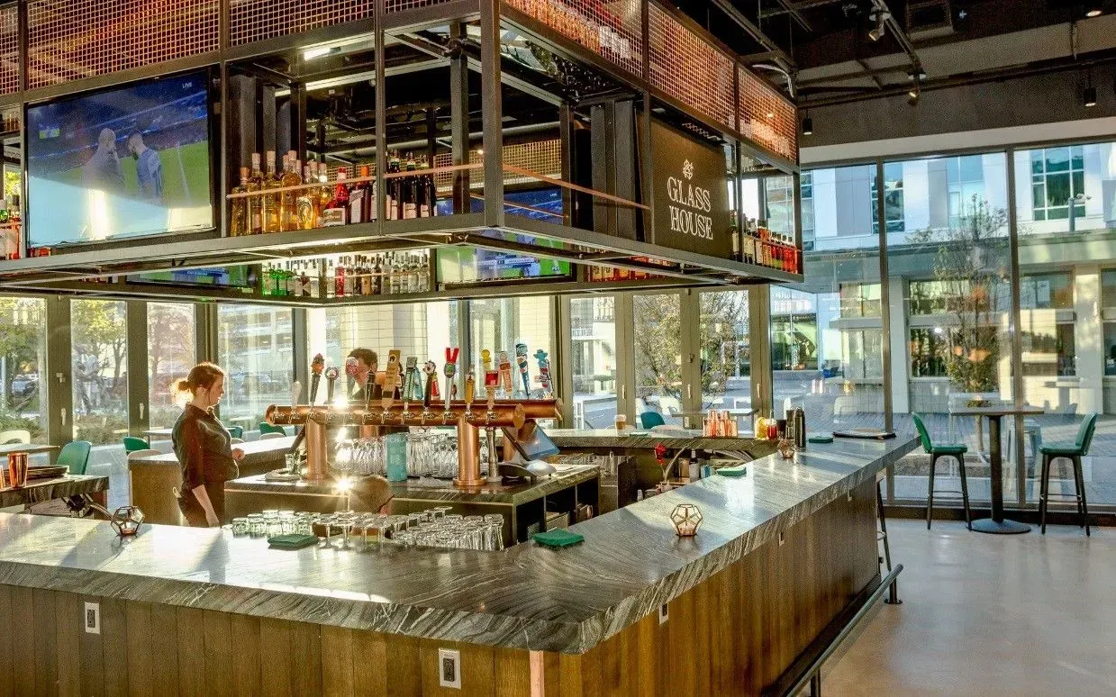 Bright modern restaurant bar with glass shelves, tables, and warm ambient lighting