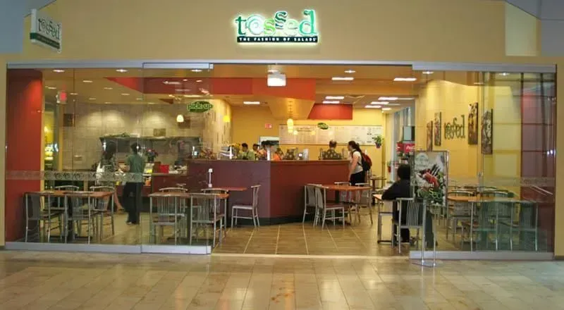 Small restaurant storefront with red counter seating and a few people inside behind glass doors.