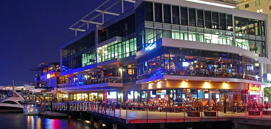 Nighttime waterfront restaurant building lit with colorful lights and reflections on the water