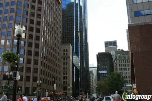 City street lined with tall office buildings and traffic, with pedestrians at the bottom.