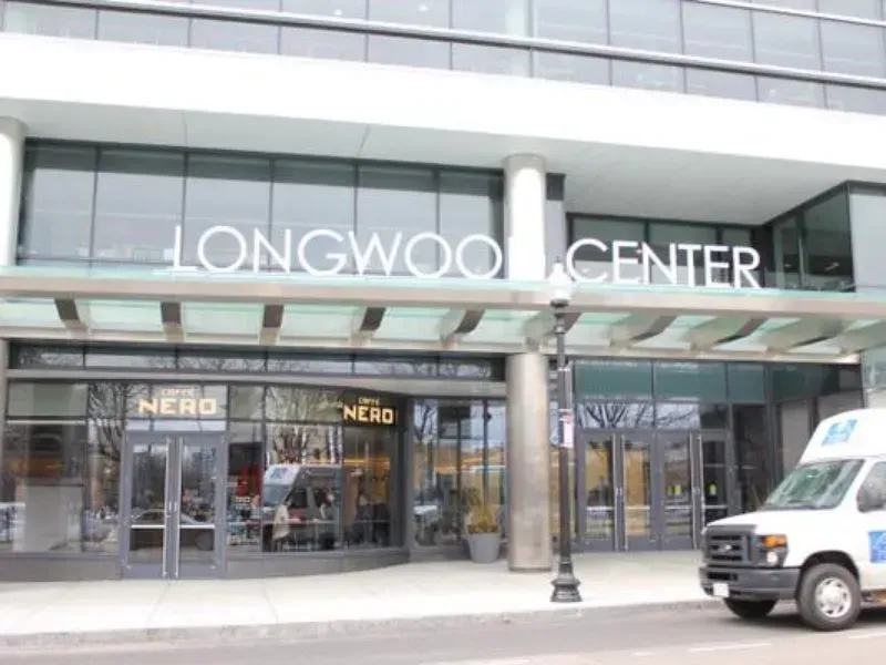 Longwood Center storefront with glass windows, signs, and a white van parked outside.
