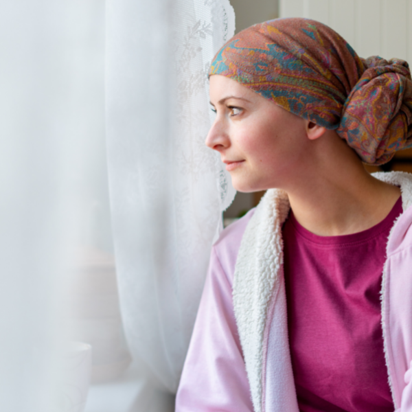 A woman wearing a head scarf is looking out of a window.