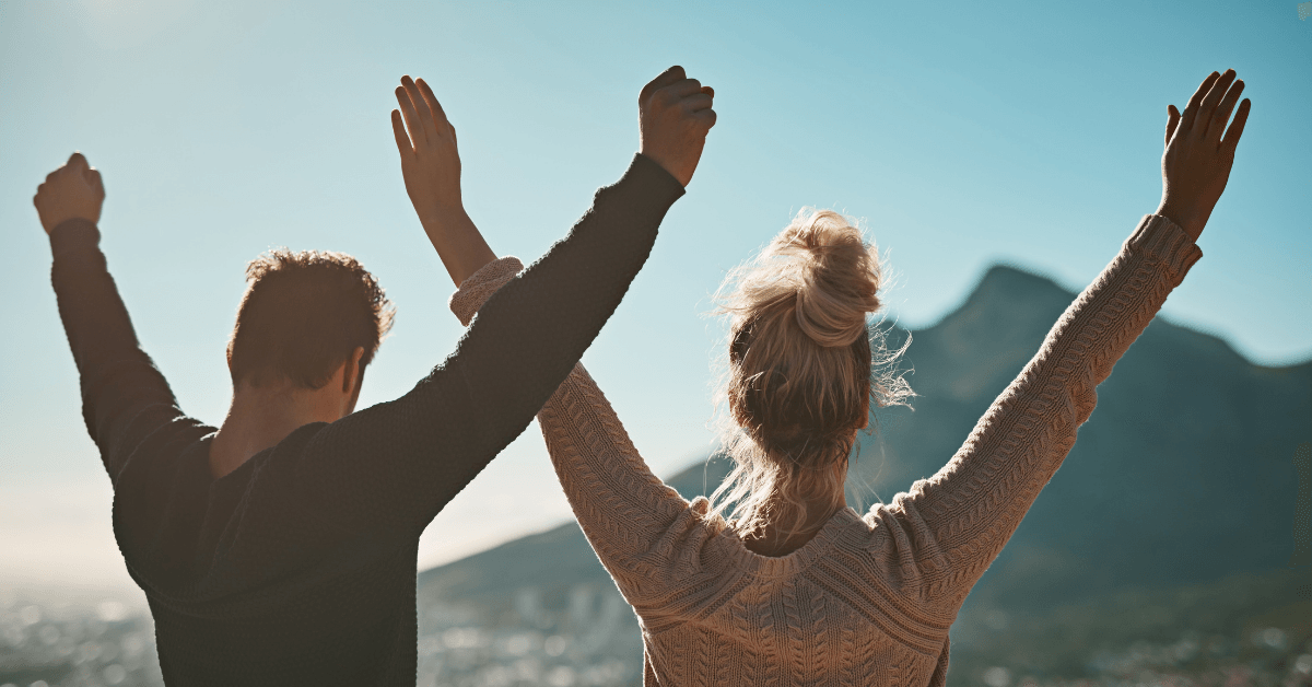 A man and a woman are standing with their arms in the air.