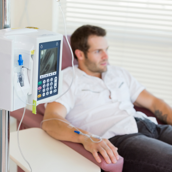 A man is sitting in a hospital chair with an iv in his arm