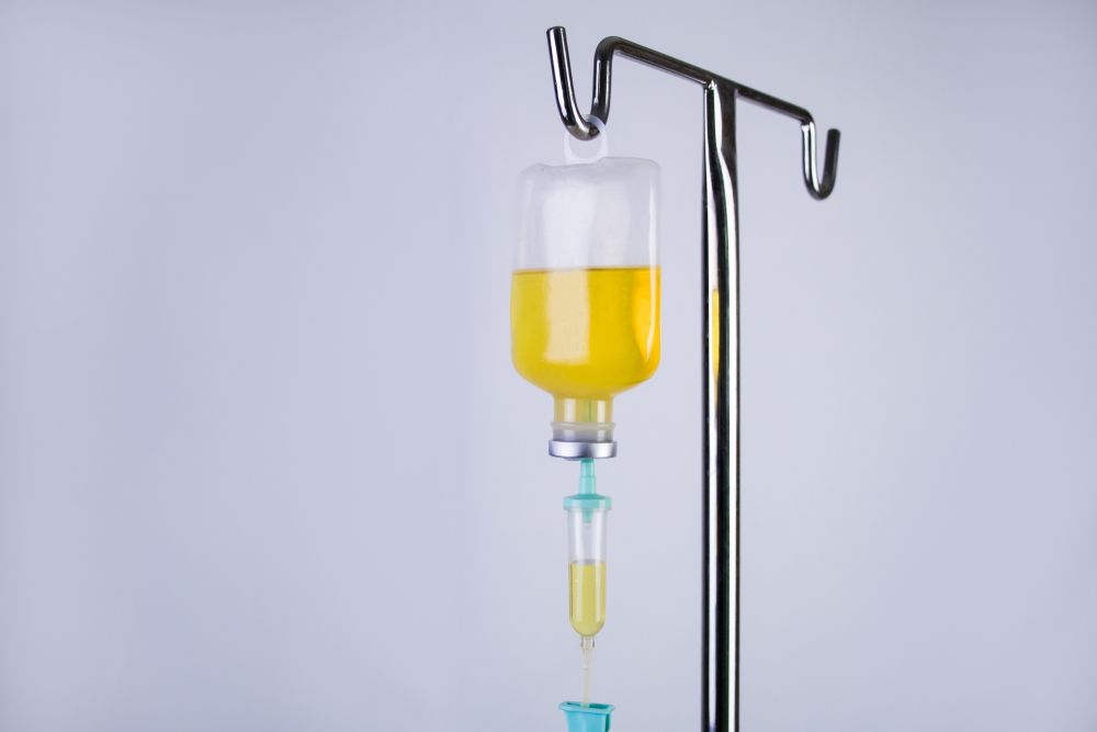 A drip with a yellow liquid hanging from it.