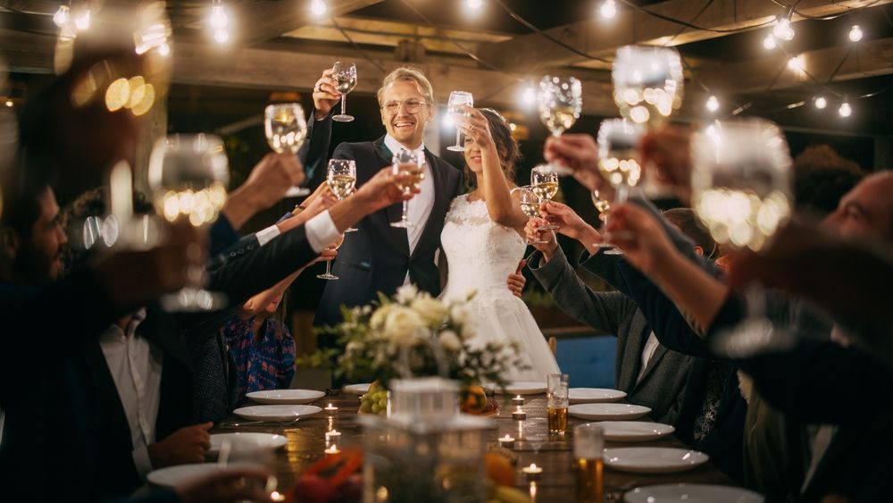 A bride and groom are toasting with wine glasses at their wedding reception.