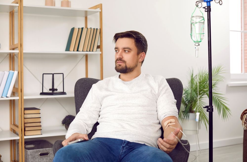 A man is sitting in a chair with an iv in his arm.