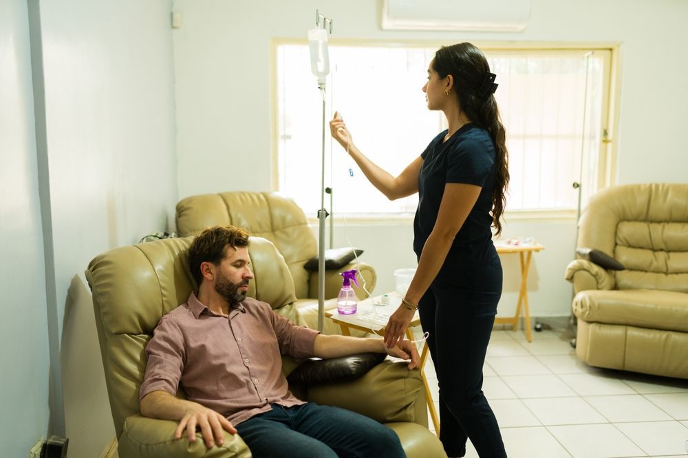 A man is sitting in a chair while a nurse stands next to him.