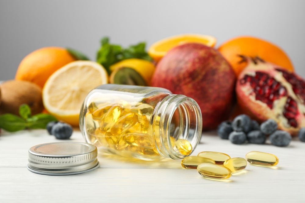 A bottle of vitamins and fruits on a table.