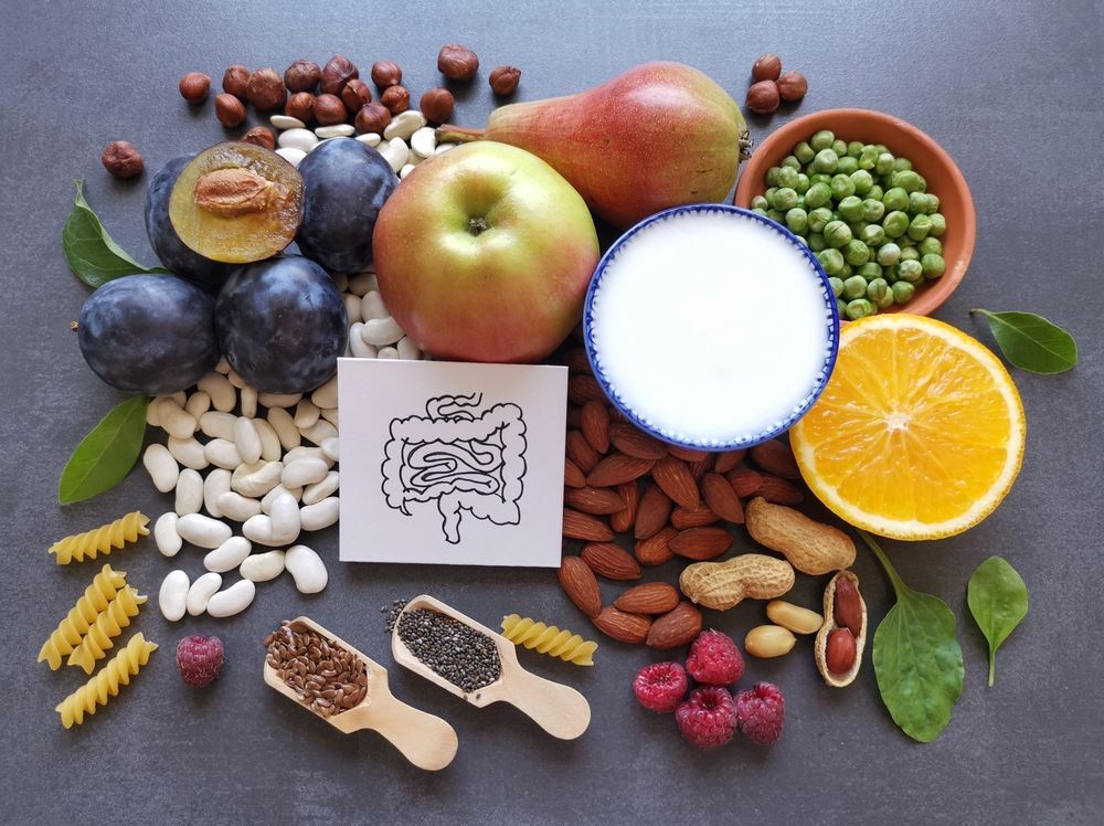A variety of fruits , vegetables , nuts , and a bowl of milk on a table.