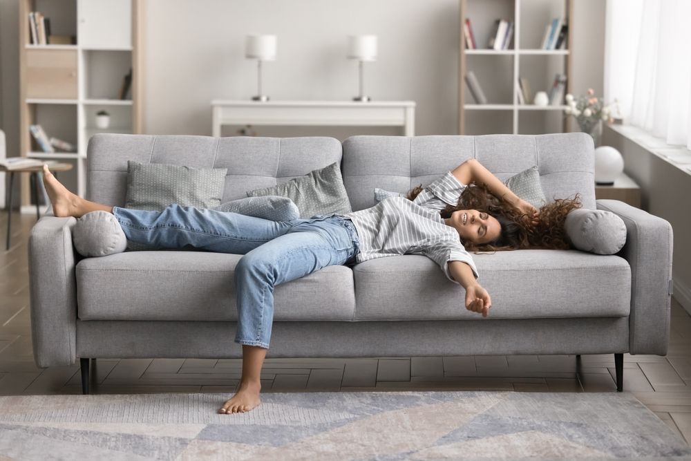 A woman is laying on a couch in a living room.